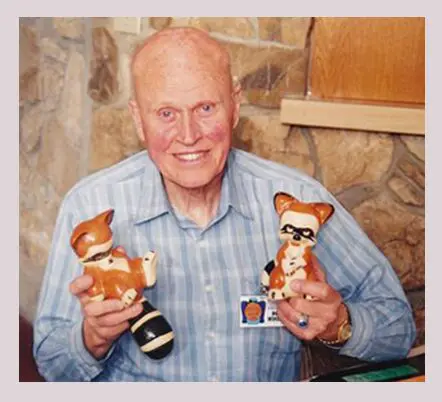 A man holding two wooden racoons in his hands.