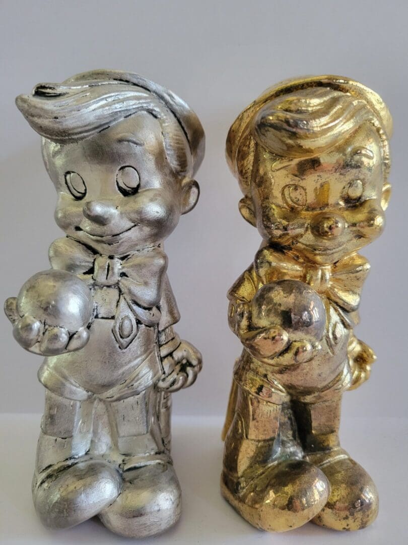 Two figurines of a boy holding a ball.