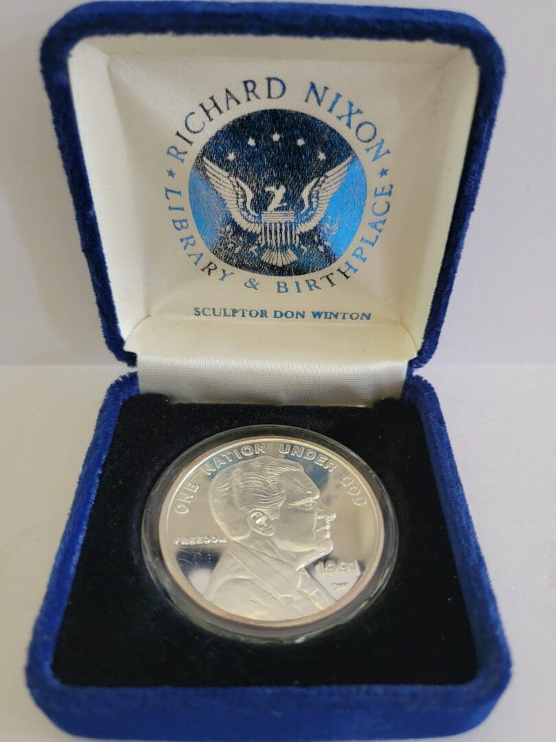 Silver coin in a blue velvet box.