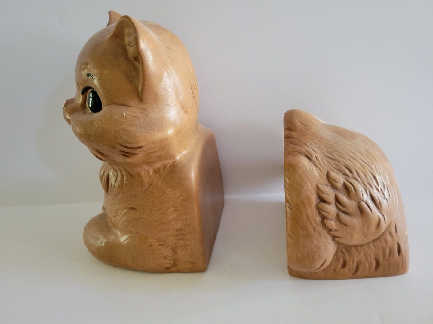 Two ceramic cat bookends on white background.