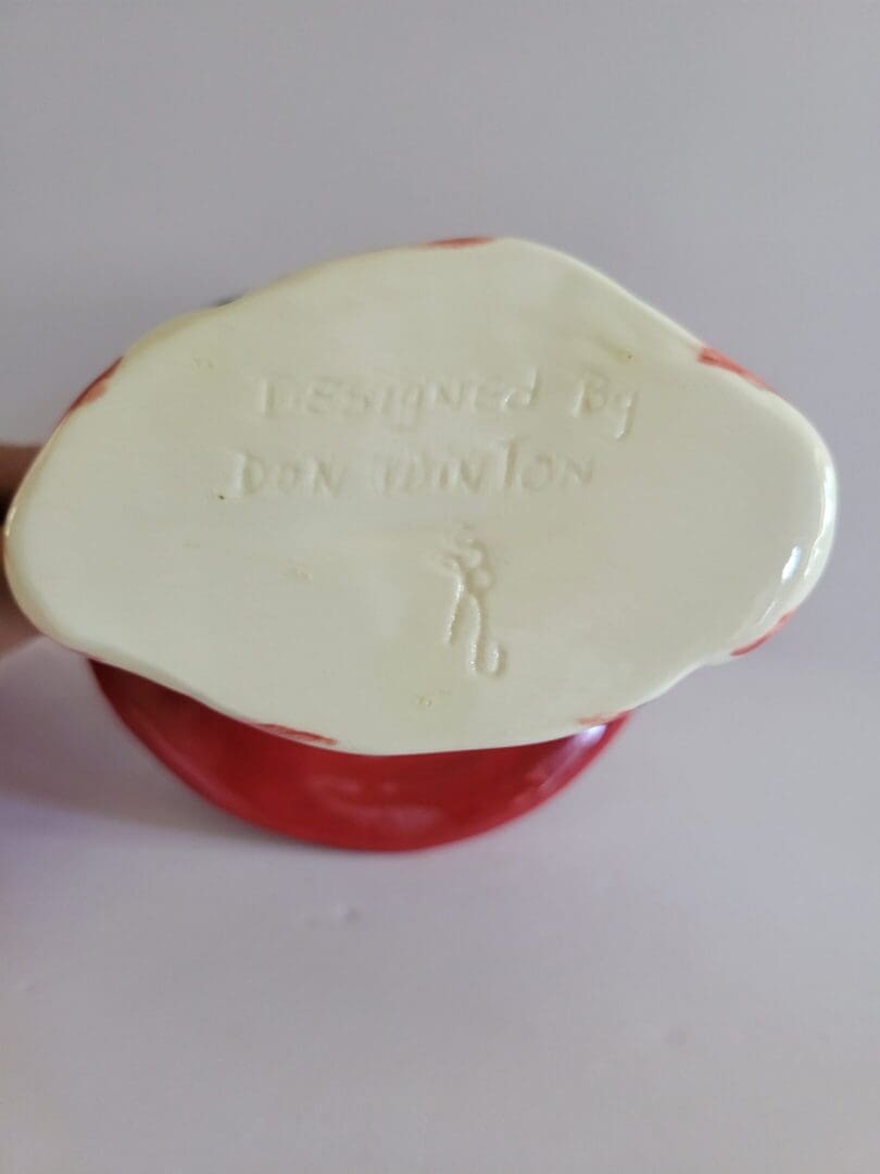 Bottom of a red ceramic figurine designed by Don Druston.