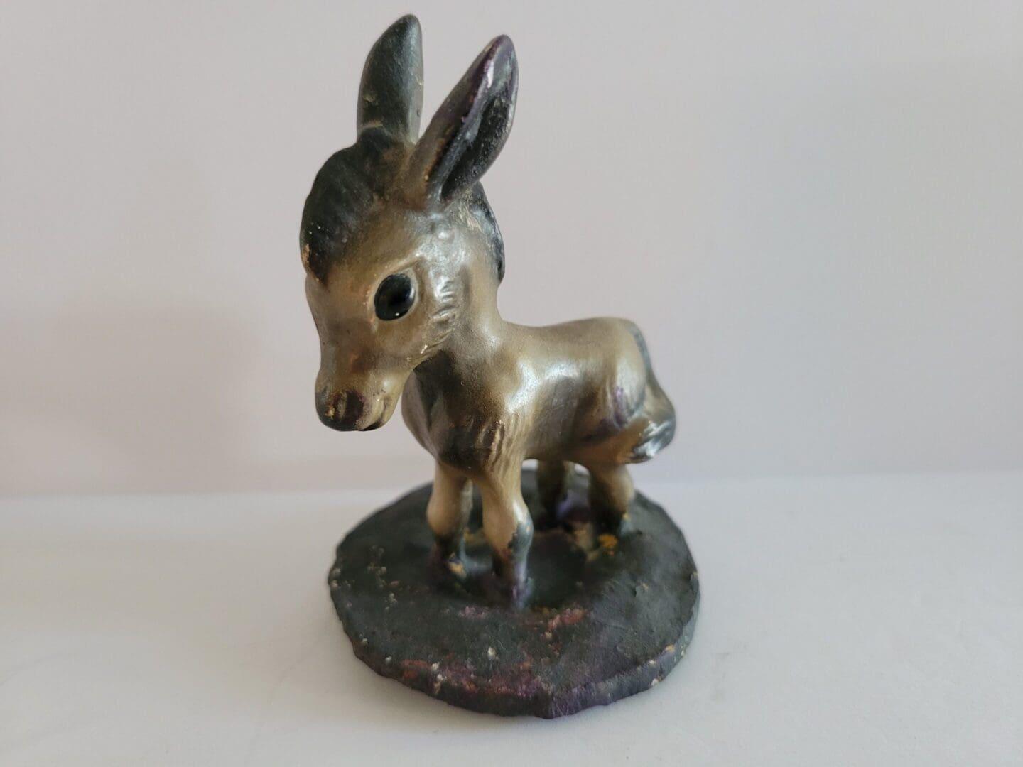 Small ceramic donkey figurine on base.