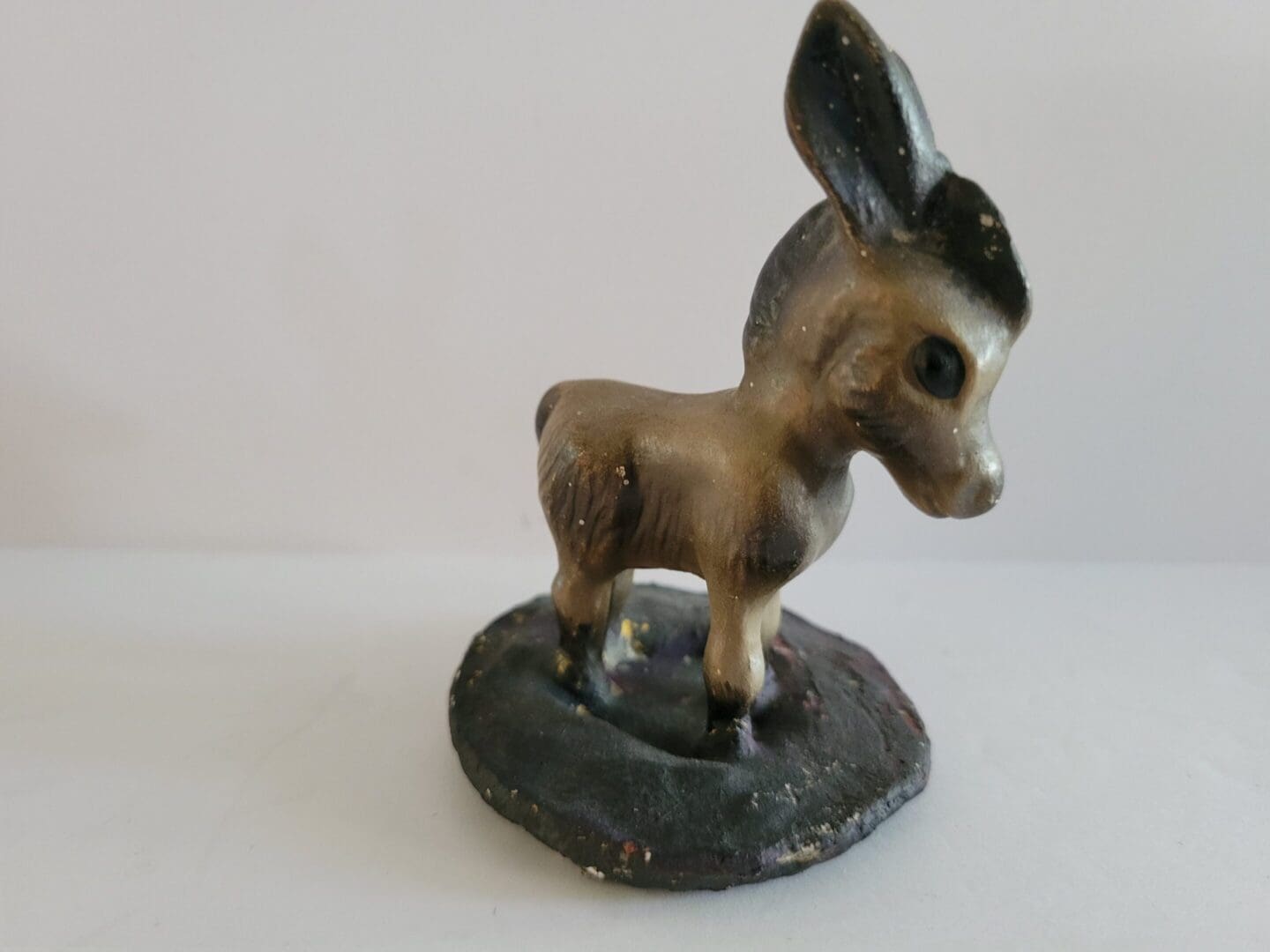 Small ceramic donkey figurine on base.