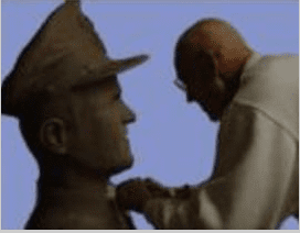 A man placing a medal on a statue.