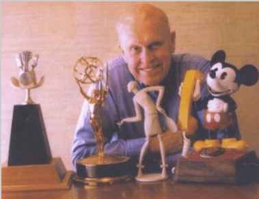 A man with awards and Mickey Mouse.