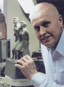 A sculptor poses with his statue of women.