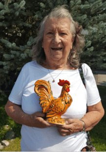 Smiling woman holding a ceramic rooster.