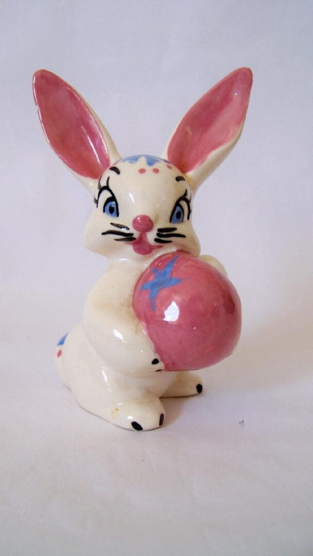 White bunny figurine holding a pink egg.