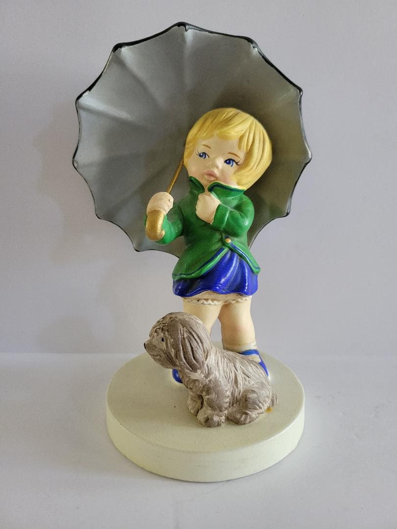 Girl with umbrella and dog figurine.