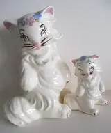 Two white ceramic cat figurines with floral details.