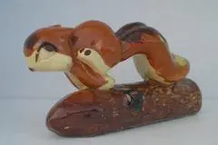 Ceramic squirrel figurine on a log.