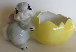 Ceramic rabbit figurine holding an egg planter.