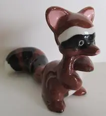 Ceramic raccoon figurine with black eyes.