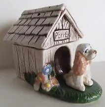 Ceramic dog house with a dog figurine.