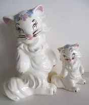 Two white ceramic cats with floral accents.