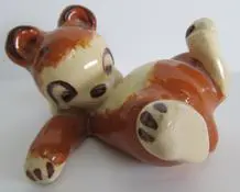 Ceramic brown and white teddy bear figurine.