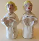 Two porcelain cherub figurines kneeling in prayer.