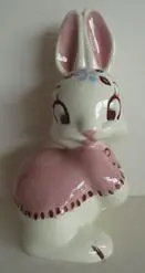 White ceramic bunny with pink ears and dress.