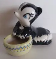 Ceramic skunk figurine with a bowl.