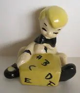 Ceramic figurine of boy writing on a block.