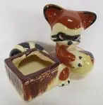 Ceramic raccoon figurine planter with open box.