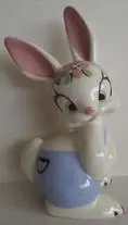 White porcelain bunny with blue pants and flowers.