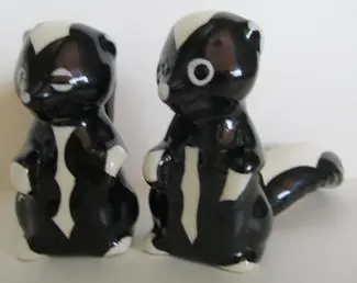 Two black and white ceramic skunk figurines.