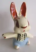 White ceramic rabbit figurine with outstretched arms.