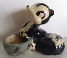 Ceramic figurine of a cartoon skunk.