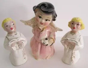 Three porcelain angel figurines singing in harmony.