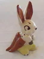 Ceramic rabbit holding a carrot figurine.