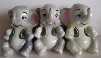 Three ceramic elephants wearing green vests.