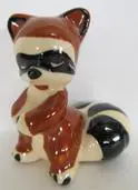 Ceramic figurine of a raccoon sitting down.