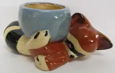 Ceramic raccoon holding a blue pot.