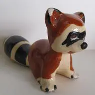 Ceramic raccoon figurine with striped tail.