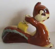 Ceramic squirrel figurine holding a yellow acorn.