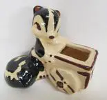 Ceramic skunk figurine pushing a wagon.