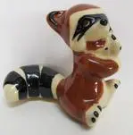 Ceramic raccoon figurine with black and white tail.