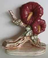 Ceramic sculpture of two red flowers on a branch.